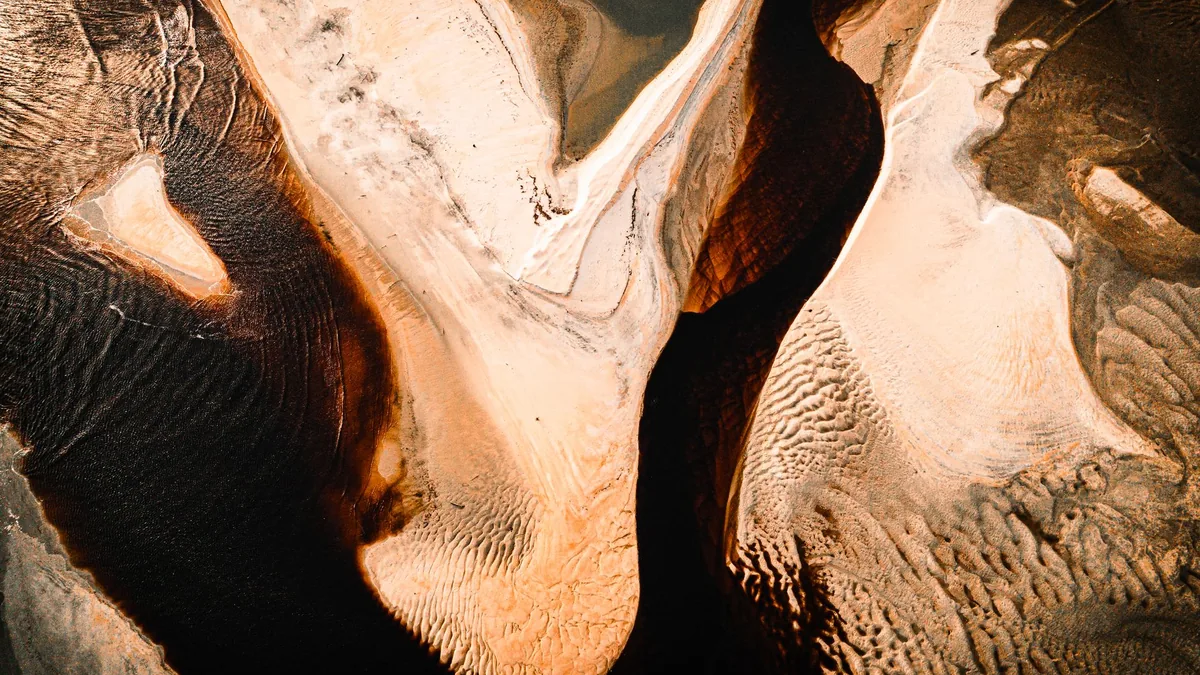 Aerial shot capturing the intricate textures and stunning patterns of desert sand dunes.